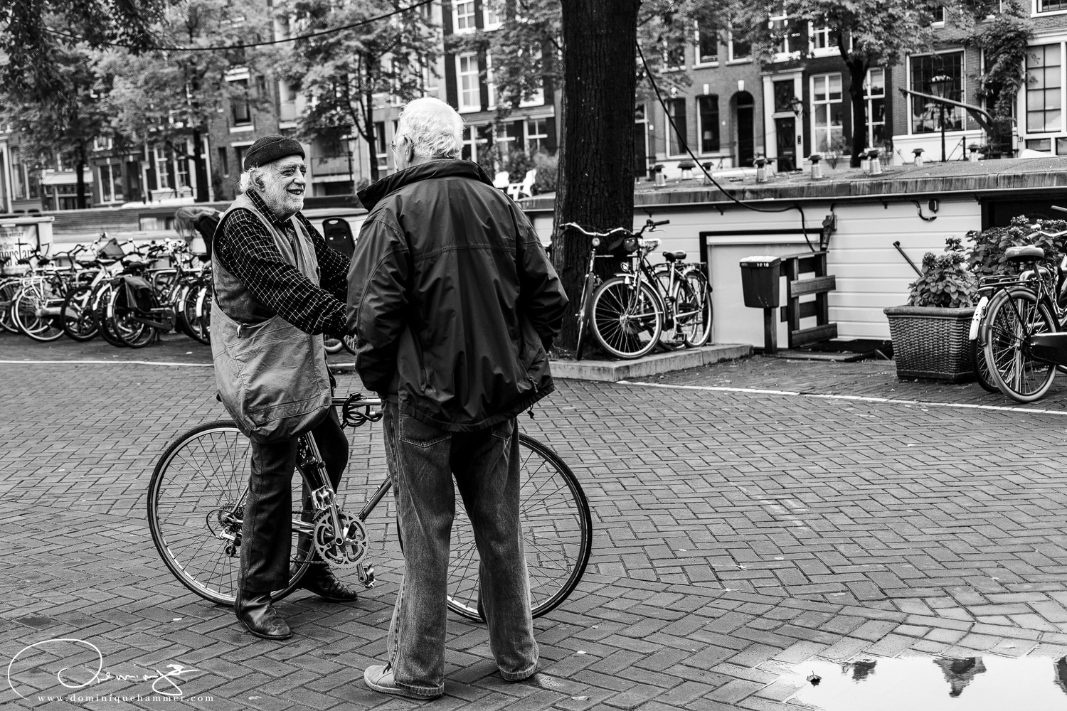 Zwei M&auml;nner mit einem Fahrrad in Amsterdam von Fotograf Dominique Hammer