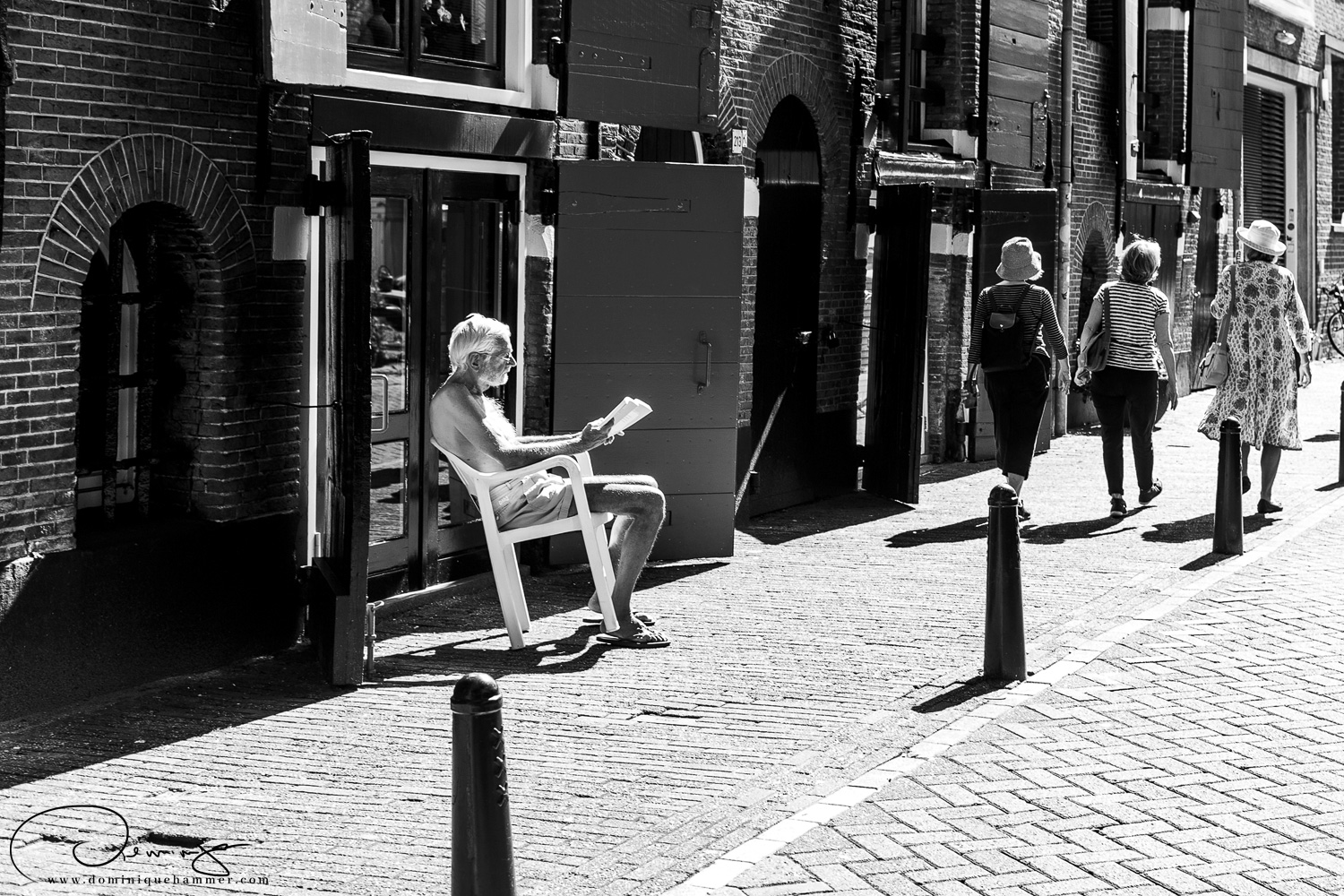 Ein Mann sitzt in einen Sessel in der Sonne und liest in Amsterdam von Fotograf Dominique Hammer